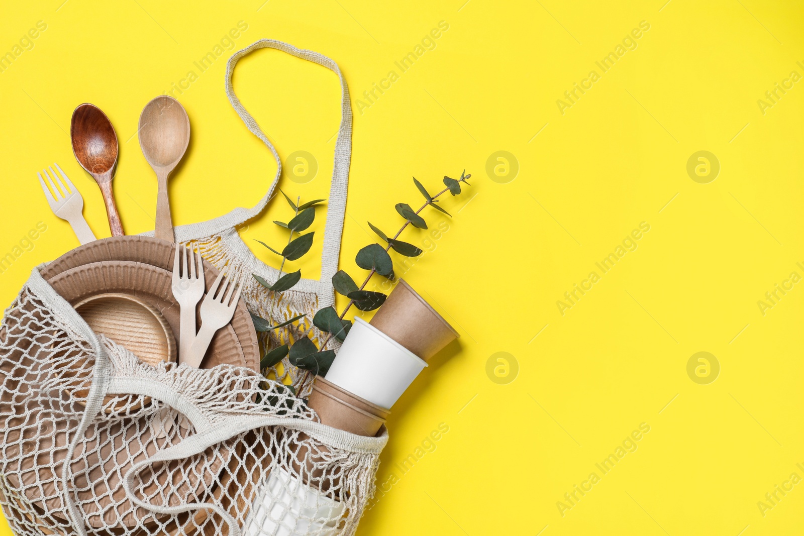 Photo of Net bag with different eco items on yellow background, top view and space for text. Recycling concept