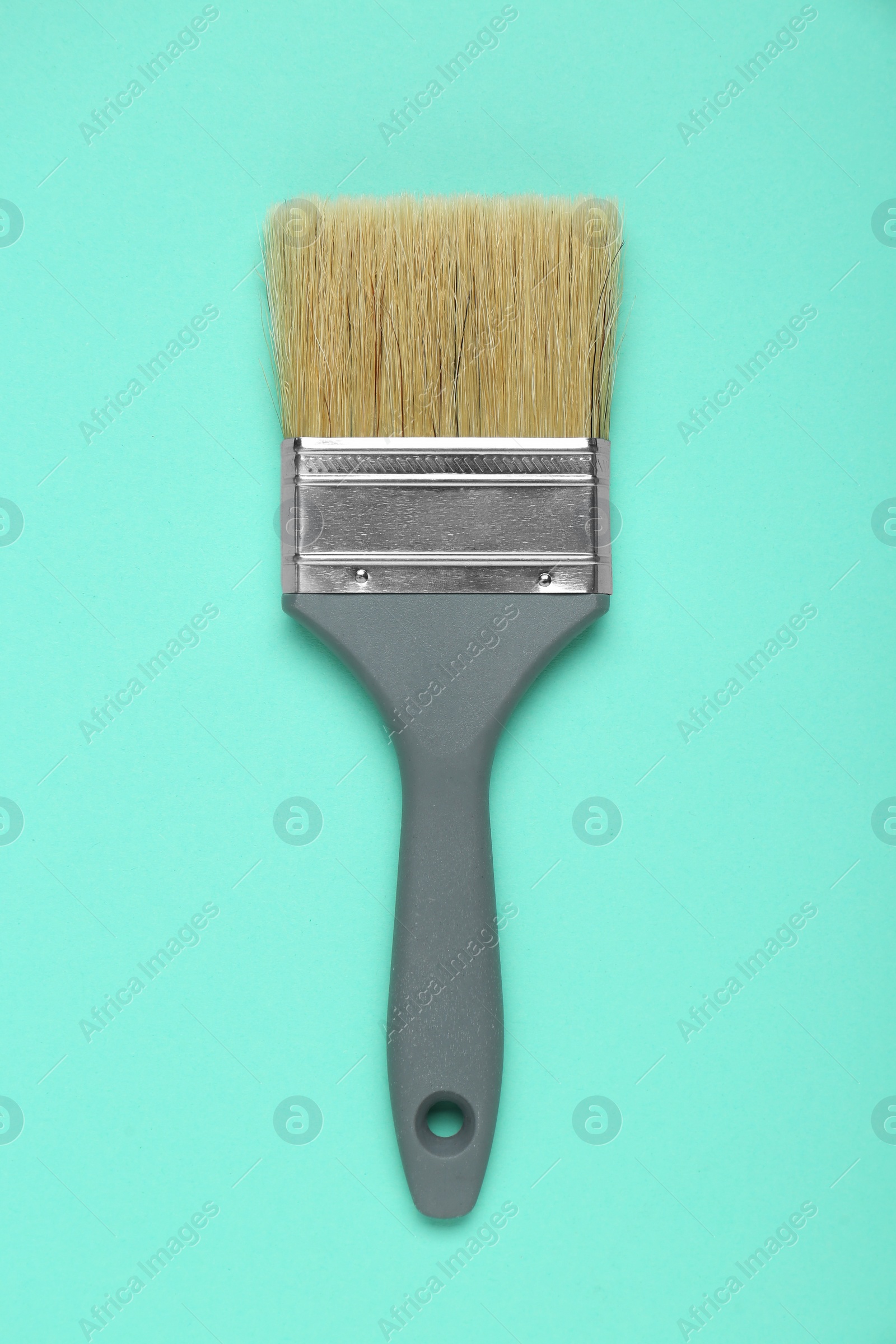 Photo of One paint brush with grey handle on turquoise background, top view
