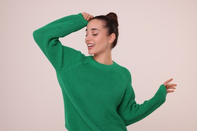 Beautiful young woman in stylish warm sweater on light grey background