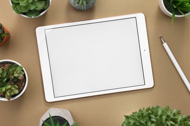 Modern tablet and houseplants on dark beige background, flat lay. Space for text