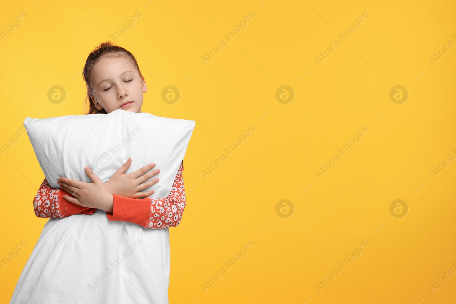 Photo of Sleepy girl with pillow on orange background, space for text. Insomnia problem