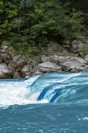 Wild mountain river flowing along rocky banks in forest