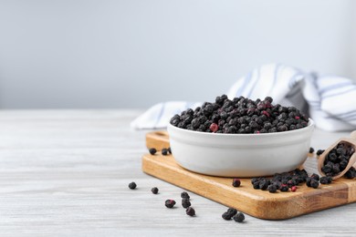 Photo of Bowl and scoop with dried blueberries on white wooden table. Space for text