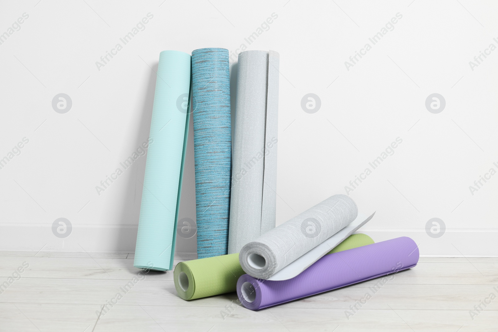 Photo of Different wallpaper rolls near white wall indoors