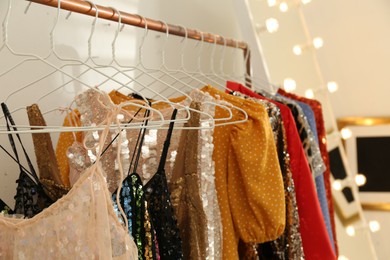 Photo of Stylish party dresses on rack indoors, closeup