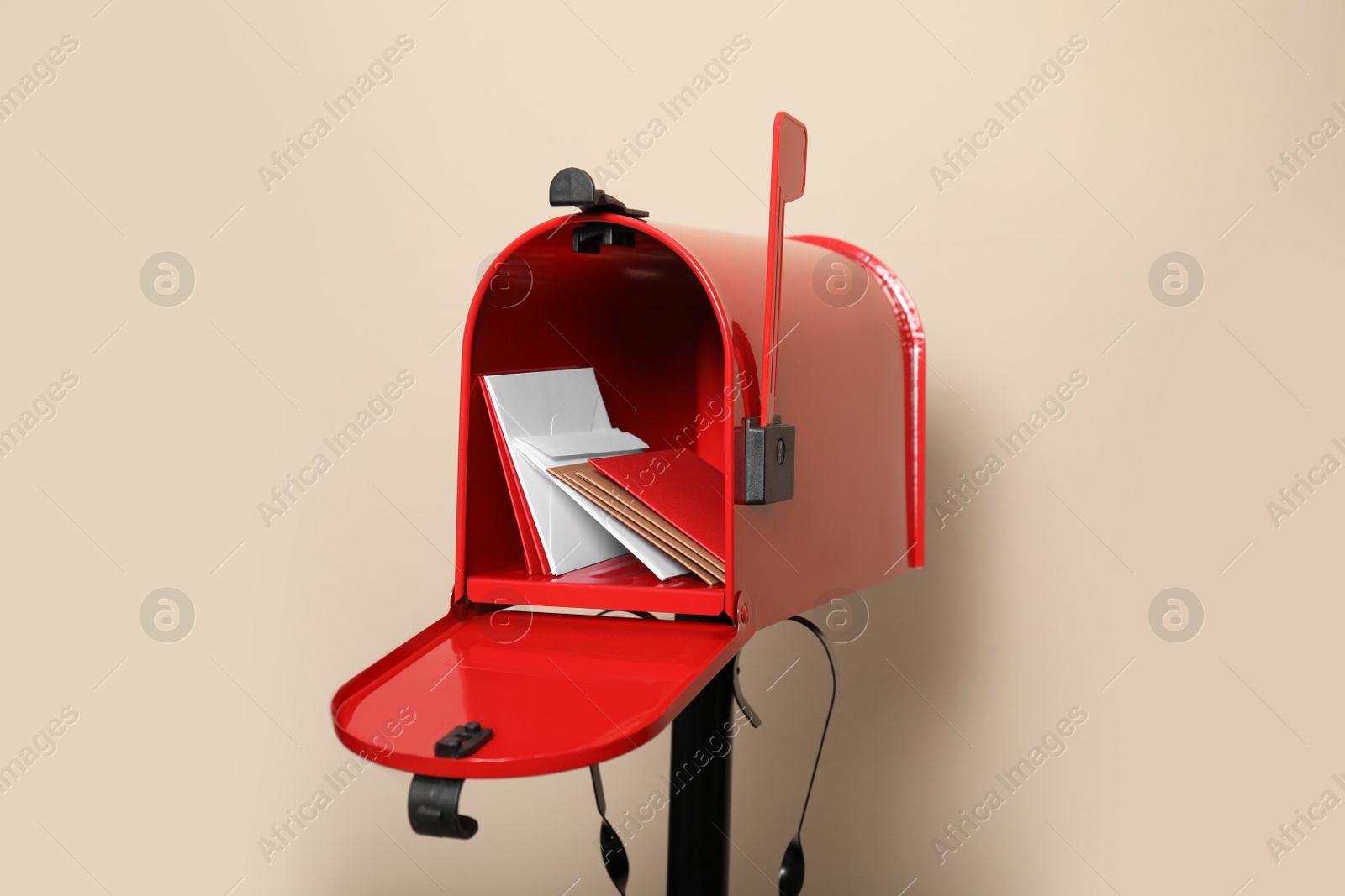 Photo of Open red letter box with envelopes against beige background