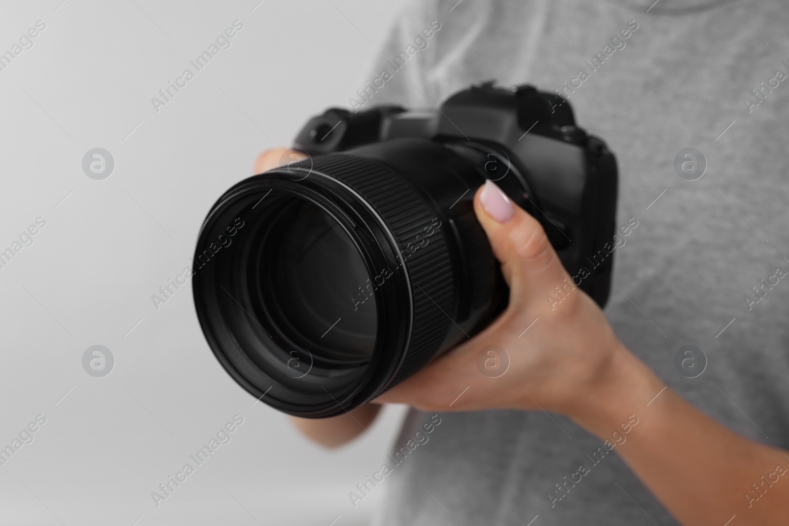 Photo of Photographer with camera on light grey background, closeup