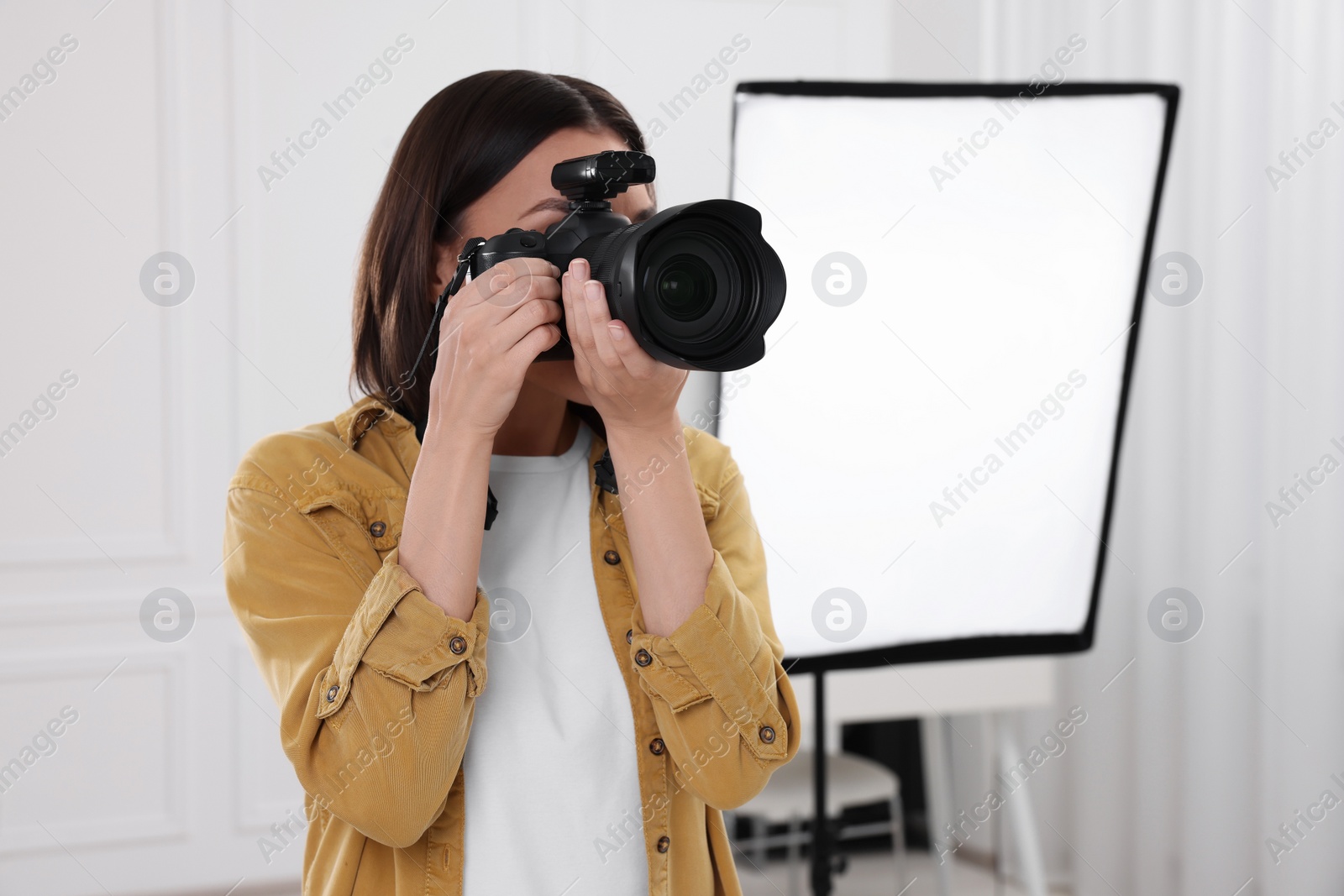 Photo of Professional photographer taking picture in modern photo studio, space for text