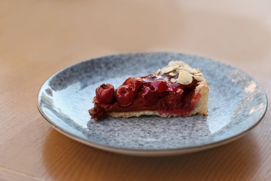 Photo of Plate with slice of cherry cake on wooden table