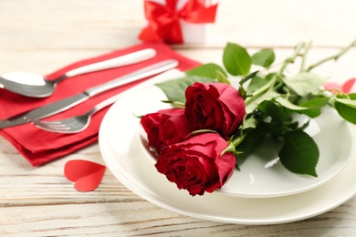 Beautiful table setting for Valentine's Day dinner with roses on white wooden background, closeup