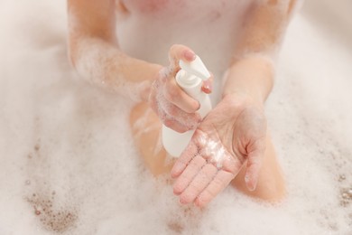 Photo of Woman applying shower gel onto hand in bath indoors, closeup