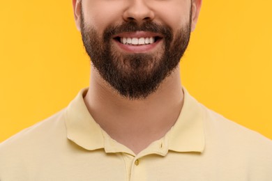 Photo of Man with clean teeth smiling on yellow background, closeup