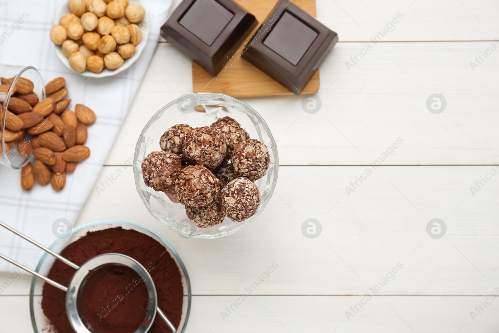 Photo of Tasty chocolate balls and ingredients on white wooden table, flat lay. Space for text