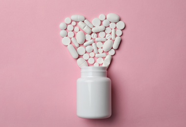 Photo of Bottle and heart of pills on color background, flat lay