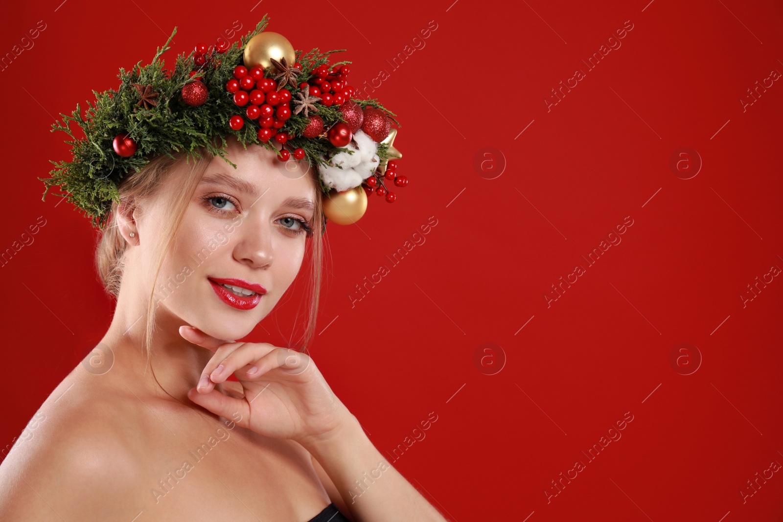 Photo of Beautiful young woman wearing Christmas wreath on red background. Space for text