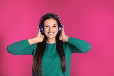 Photo of Attractive young woman enjoying music in headphones on color background