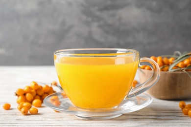 Photo of Fresh sea buckthorn tea on white wooden table, closeup