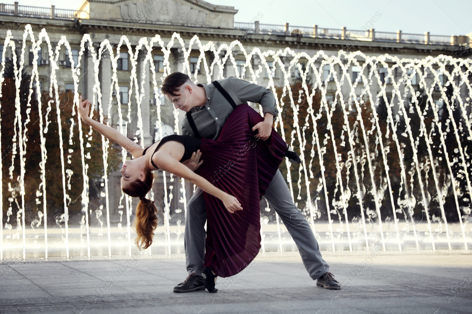 Photo of Beautiful young couple practicing dance moves near fountain outdoors