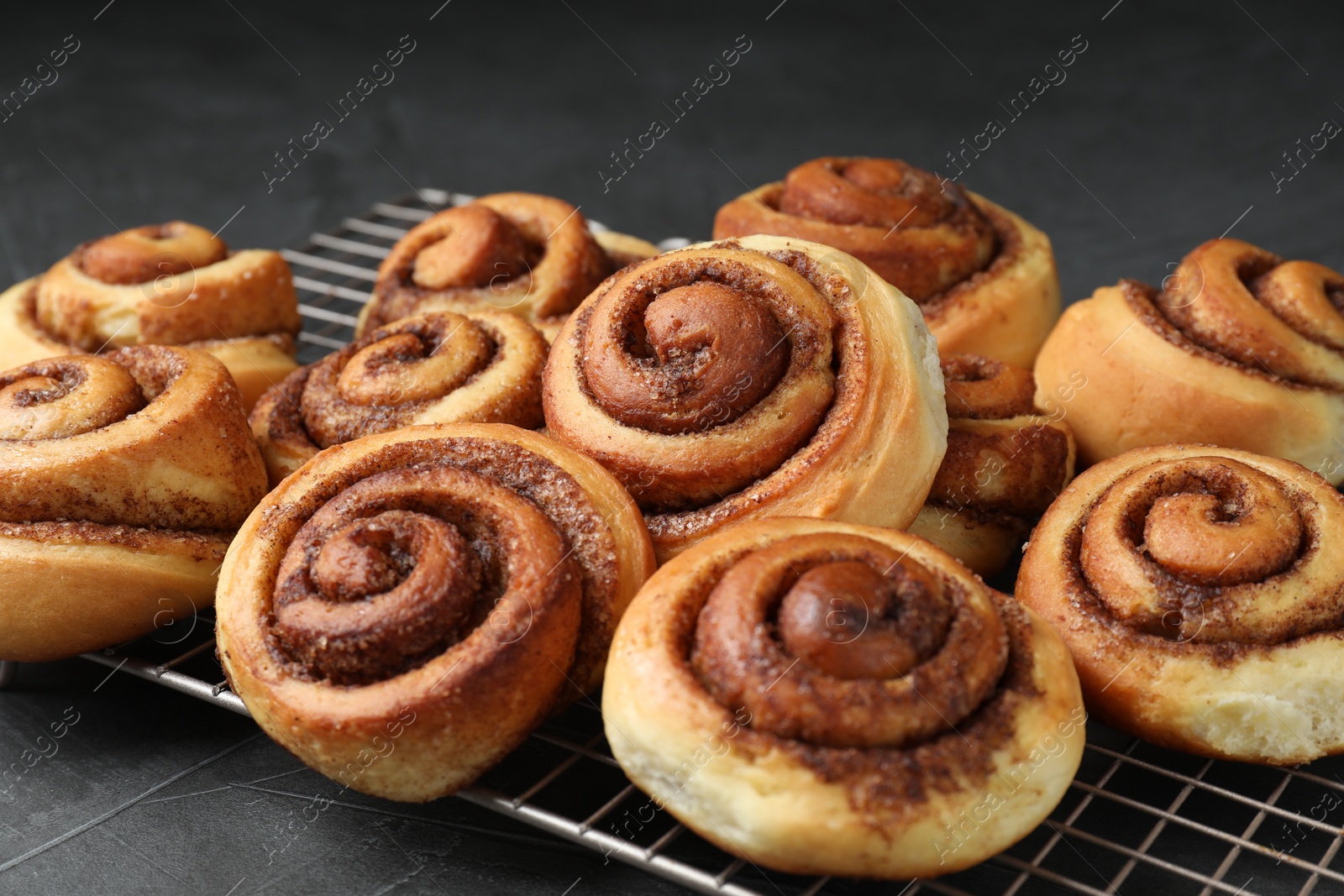 Photo of Tasty cinnamon rolls on black table, closeup