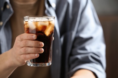 Photo of Man with glass of cold cola indoors, closeup