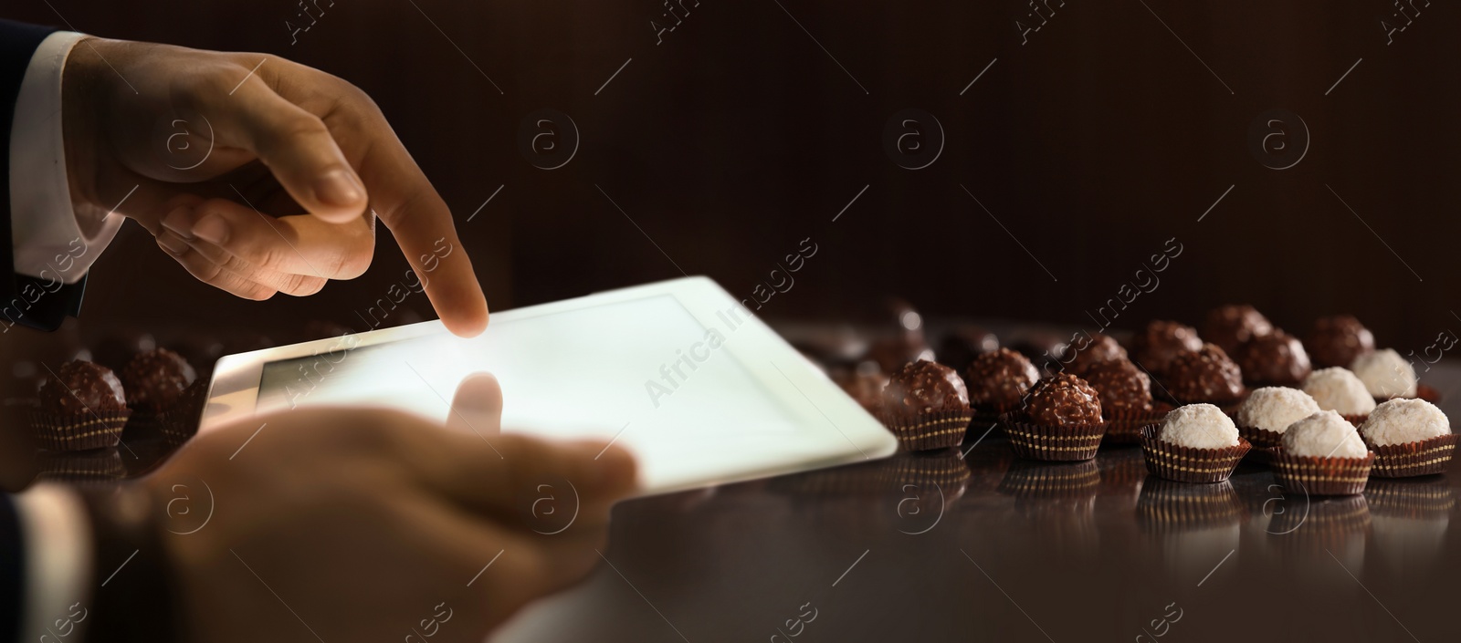 Image of Production line of chocolate candies. Man working with tablet, closeup. Banner design