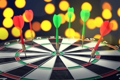 Image of Dart board with color arrows hitting target against blurred background, bokeh effect