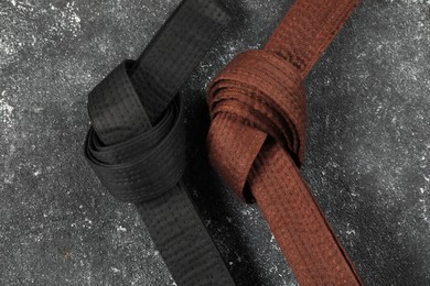 Photo of Black and brown karate belts on gray textured background, flat lay