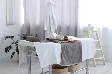 Rolled towel and spa products on massage table in recreational center