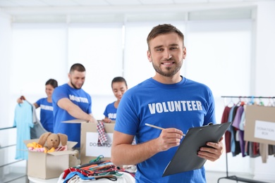 Photo of Male volunteer with clipboard listing donations indoors