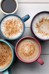 Many different cups with aromatic hot coffee on white wooden table, flat lay