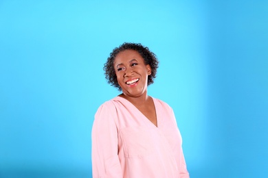 Portrait of happy African-American woman on light blue background