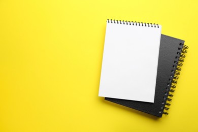 Photo of Notebooks on yellow background, top view. Space for text