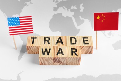 Words Trade War made of wooden cubes, American and Chinese flags on world map