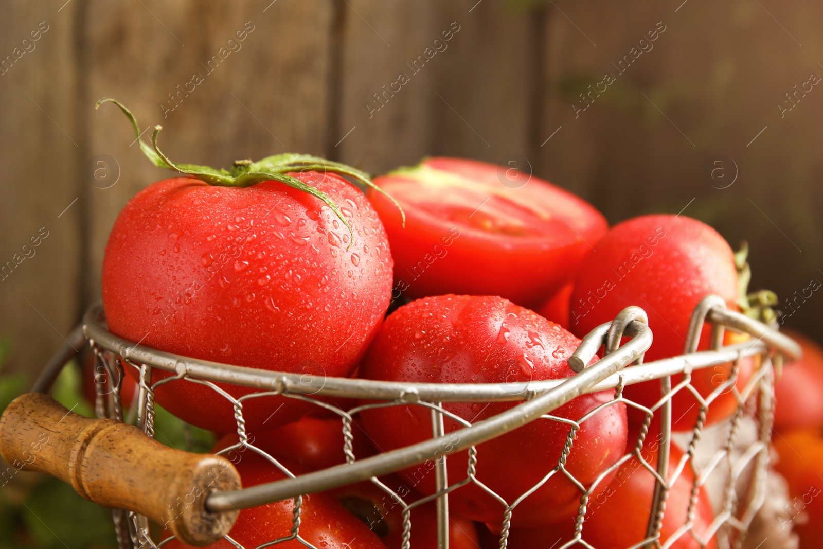 Photo of Fresh ripe tomatoes in metal basket, closeup