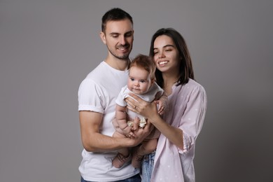 Photo of Happy family. Couple with their cute baby on grey background