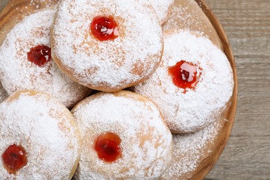 Delicious donuts with jelly and powdered sugar on wooden table, closeup