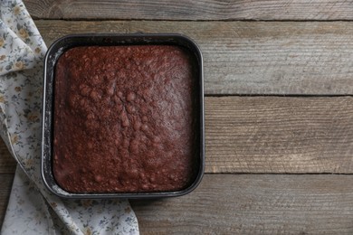 Photo of Homemade chocolate sponge cake on wooden table, top view. Space for text