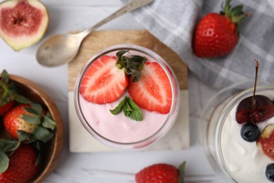 Tasty yogurt, berries and mint on white textured table, flat lay