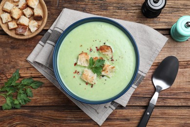 Photo of Delicious asparagus soup with croutons served on wooden table, flat lay