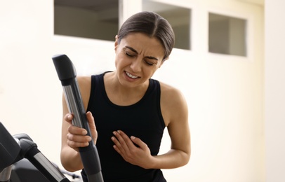 Young woman having heart attack on treadmill in gym