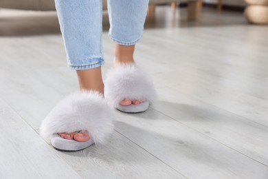 Photo of Woman wearing soft slippers at home, closeup of legs