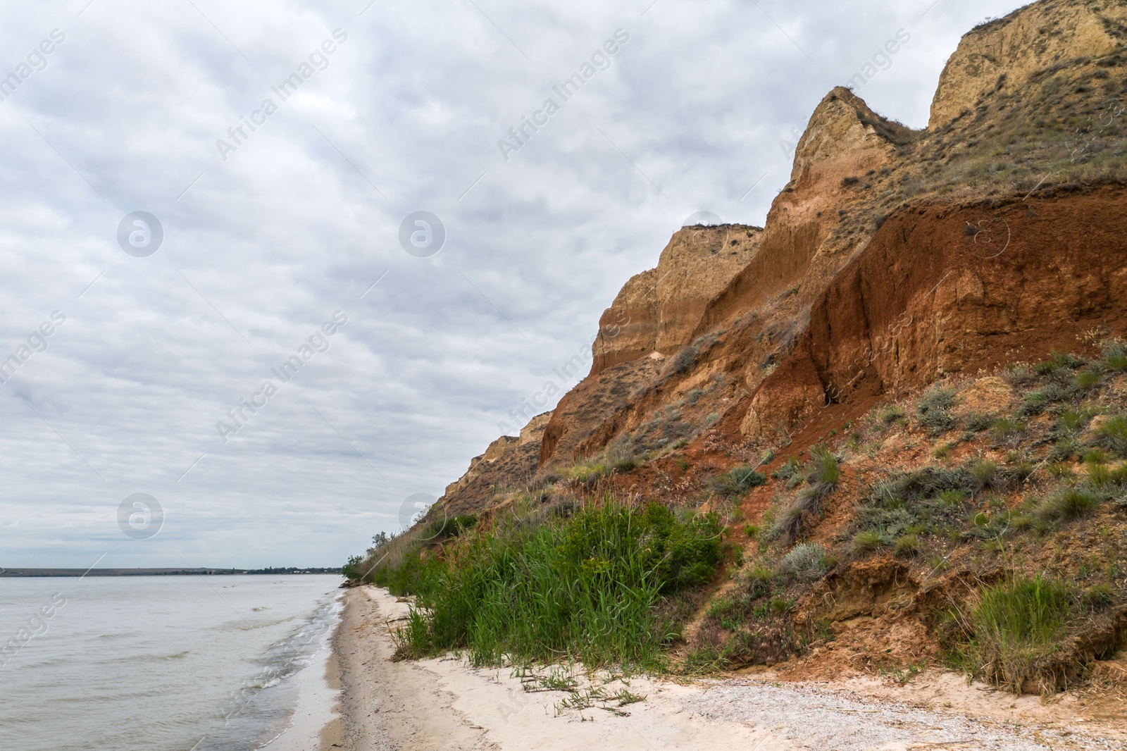 Image of Picturesque view of river bank with hill on cloudy day