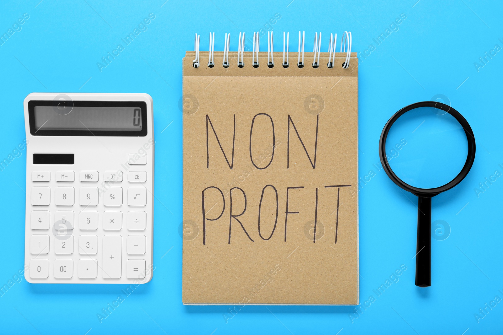 Photo of Notebook with phrase Non Profit, calculator and magnifying glass on light blue background, flat lay