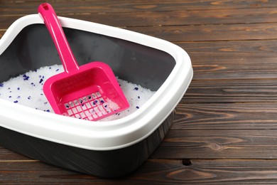 Photo of Cat litter tray with filler and scoop on wooden background