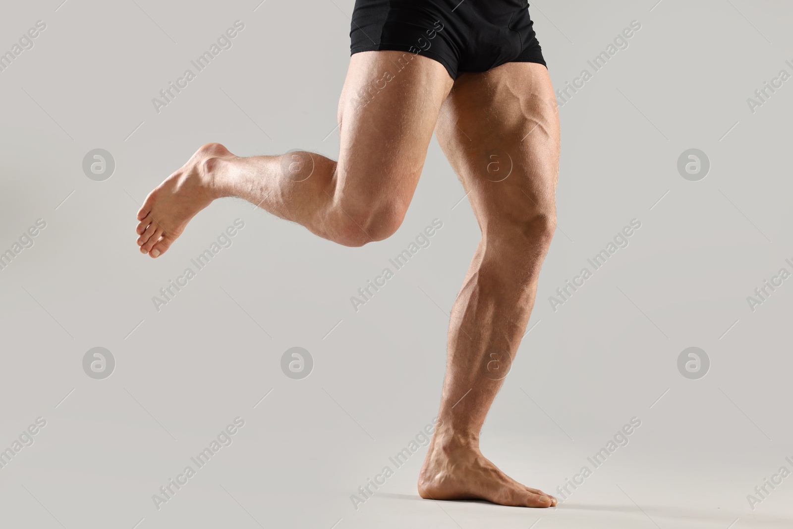 Photo of Man with muscular legs on light grey background, closeup