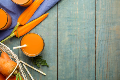 Photo of Freshly made carrot juice on wooden table, flat lay. Space for text