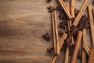 Photo of Aromatic cinnamon sticks and anise on wooden table, flat lay. Space for text