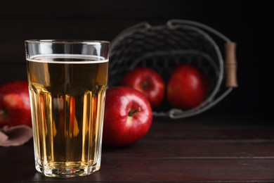 Photo of Glass of delicious cider and ripe red apples on wooden table. Space for text