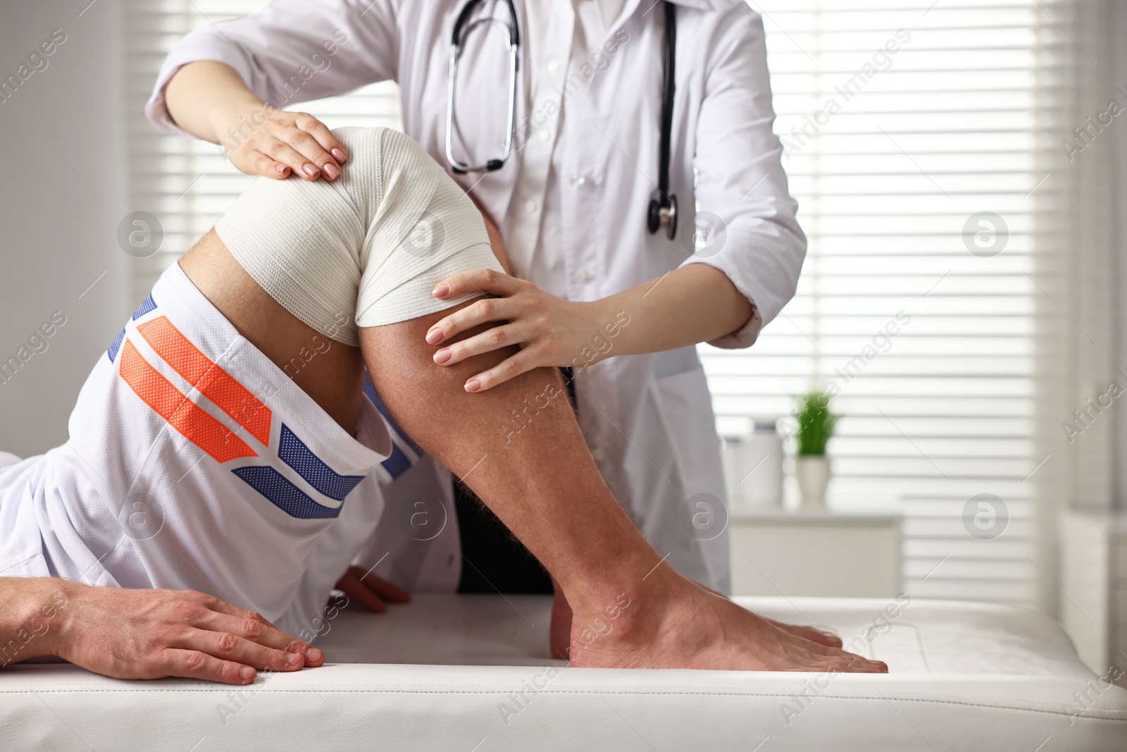 Photo of Sports injury. Doctor examining patient's knee in hospital, closeup