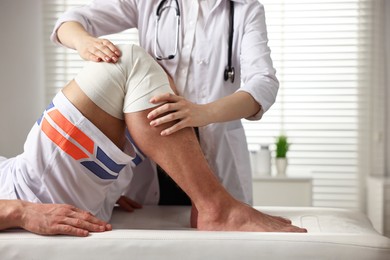 Sports injury. Doctor examining patient's knee in hospital, closeup